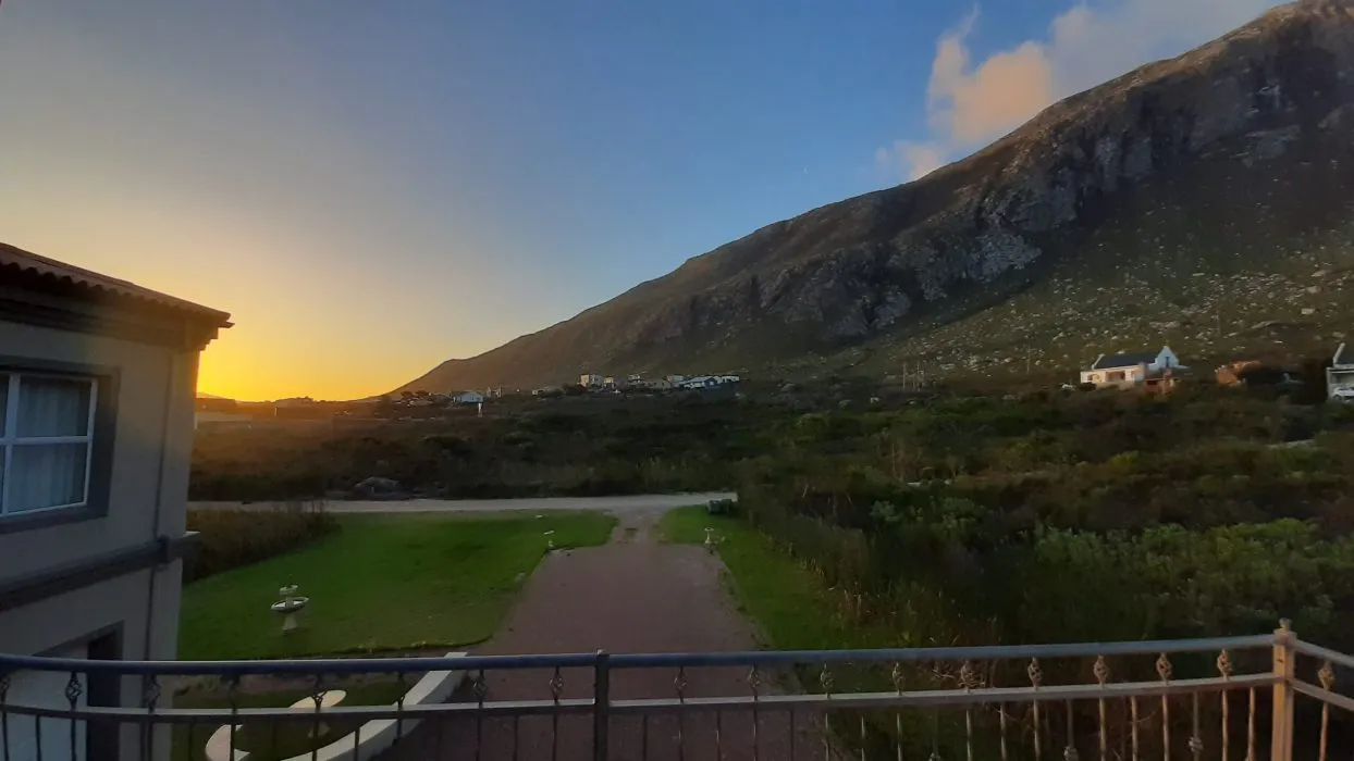 Sunset view from a balcony with mountains and houses in the background