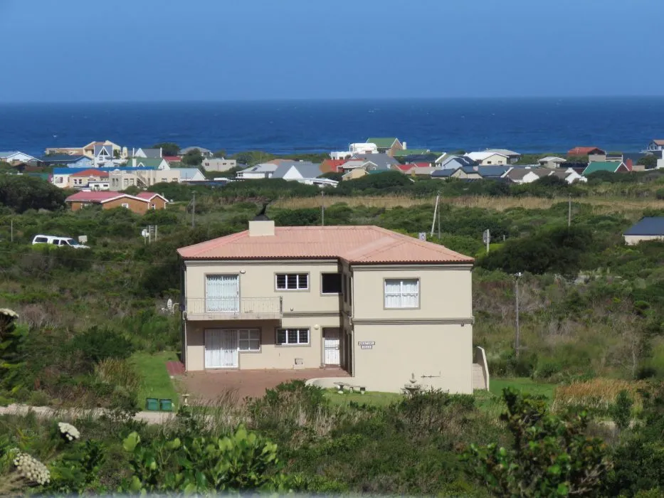 House with red roof overlooking ocean and village in a coastal area