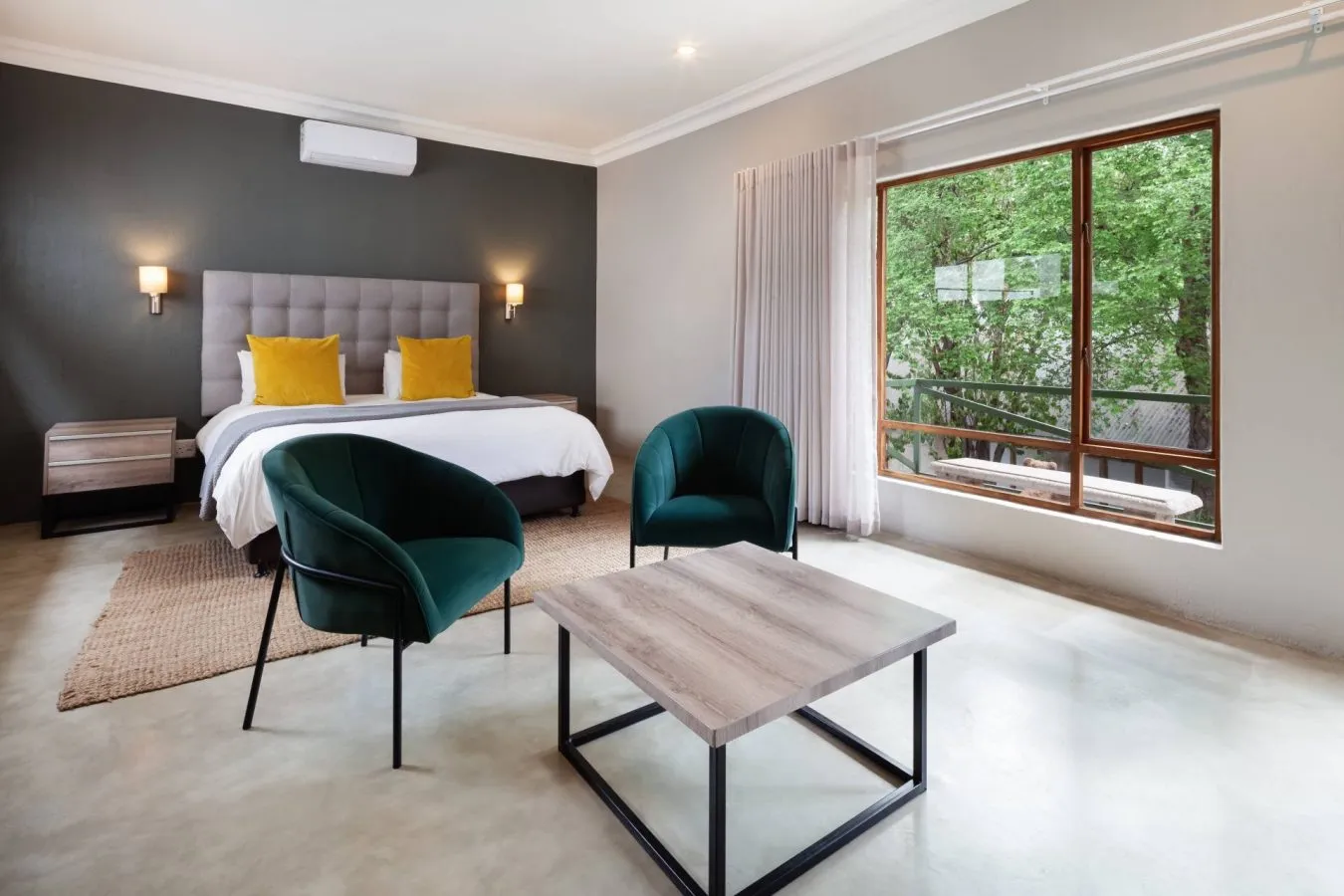 Modern bedroom with two beds green chairs wooden table and large window