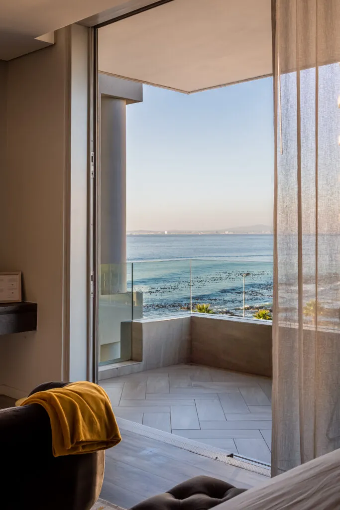 Balcony with ocean view chair with yellow towel and sheer curtains
