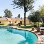 House with a swimming pool and garden area in a sunny day