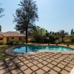 Swimming pool in a backyard with a house and trees in the background