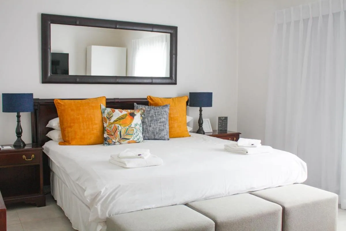 A neatly made bed with orange and patterned pillows in a bright bedroom