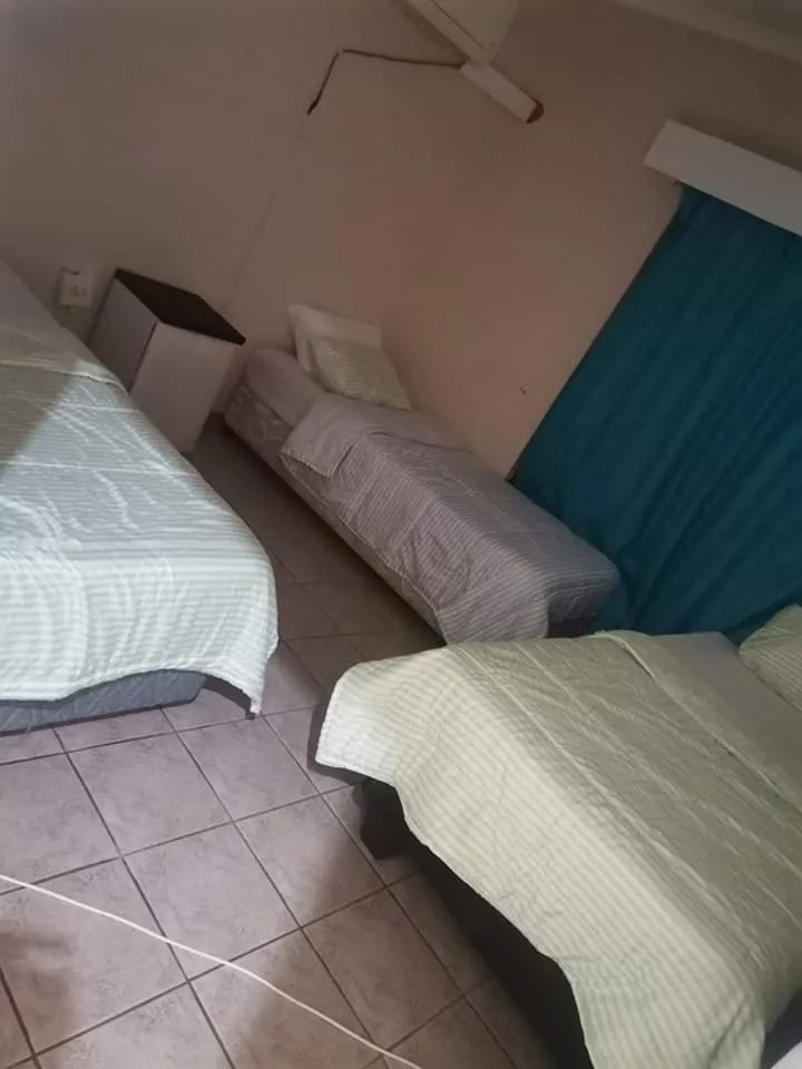 Bedroom with three single beds tiled floor and blue curtains