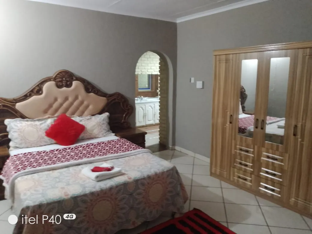 Bedroom with a large bed patterned bedding and wooden wardrobe on tiled floor