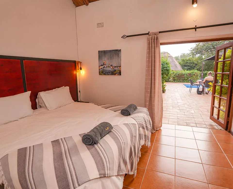 Bedroom with open door leading to outdoor patio with pool and garden