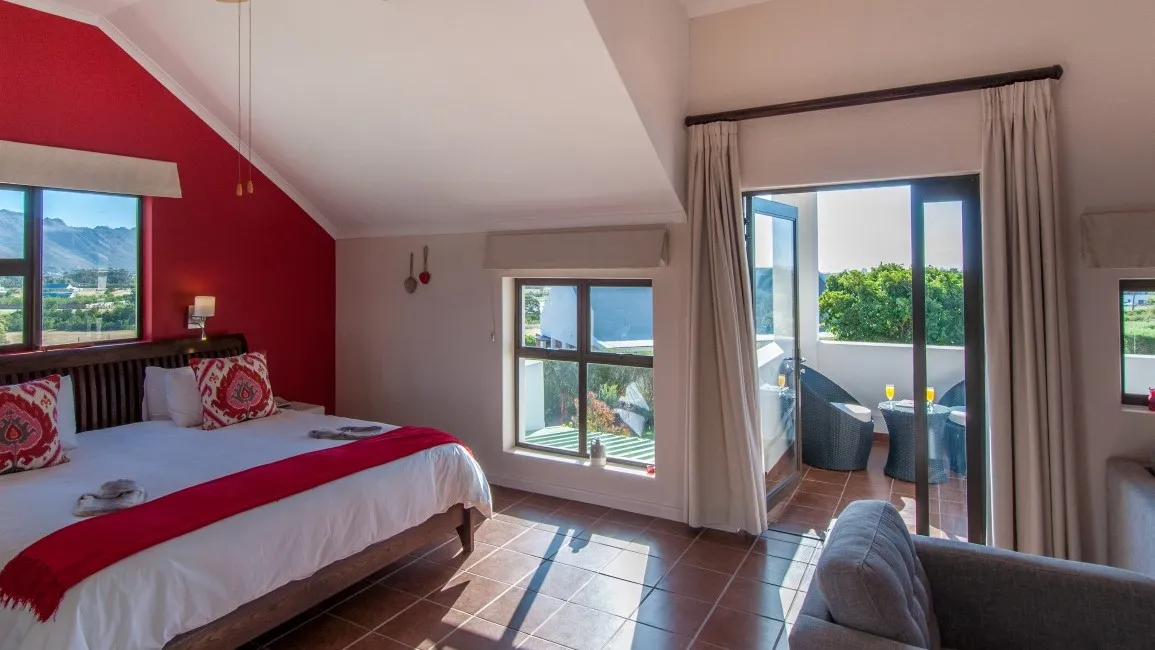 Bedroom with red accents large windows and a view of greenery outside