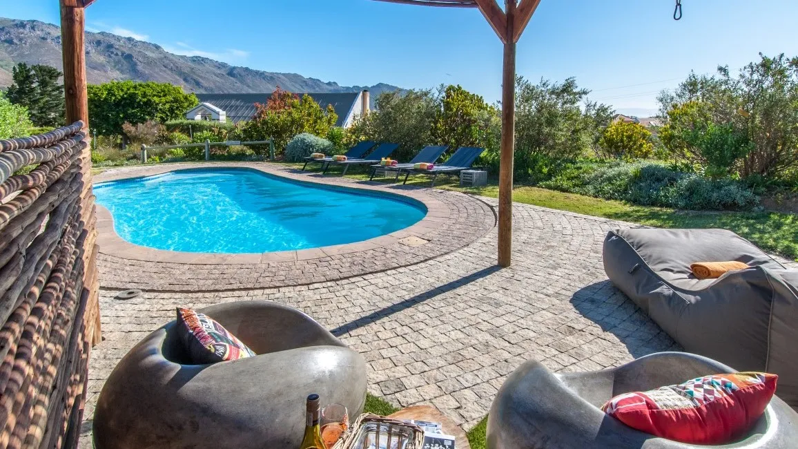 Swimming pool with lounge chairs and bean bags in a garden setting