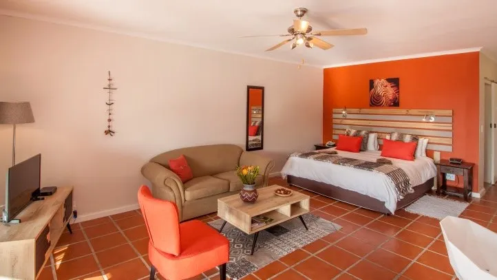 Cozy bedroom with orange accents bed sofa TV and ceiling fan