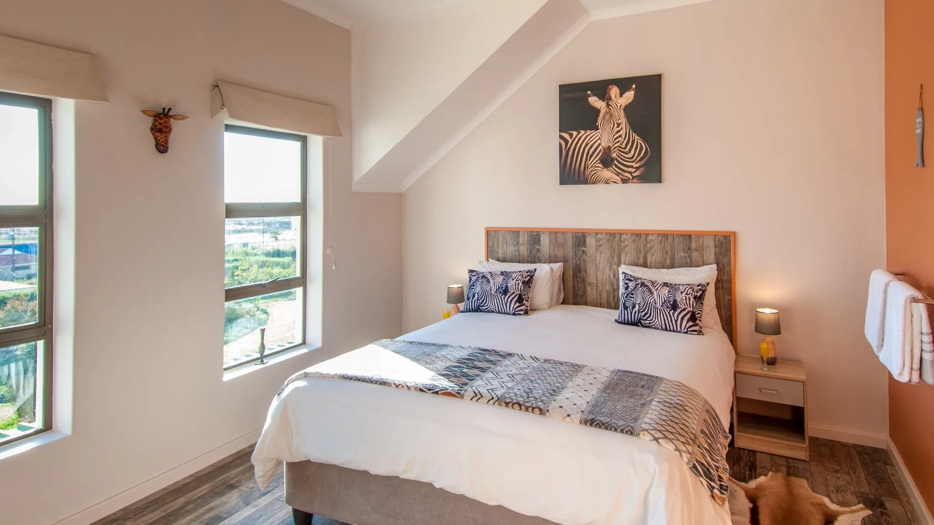 Cozy bedroom with a large bed zebra artwork and large windows with a view