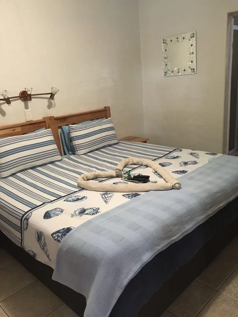 Bed with nauticalthemed bedding and a towel heart decoration in a cozy room
