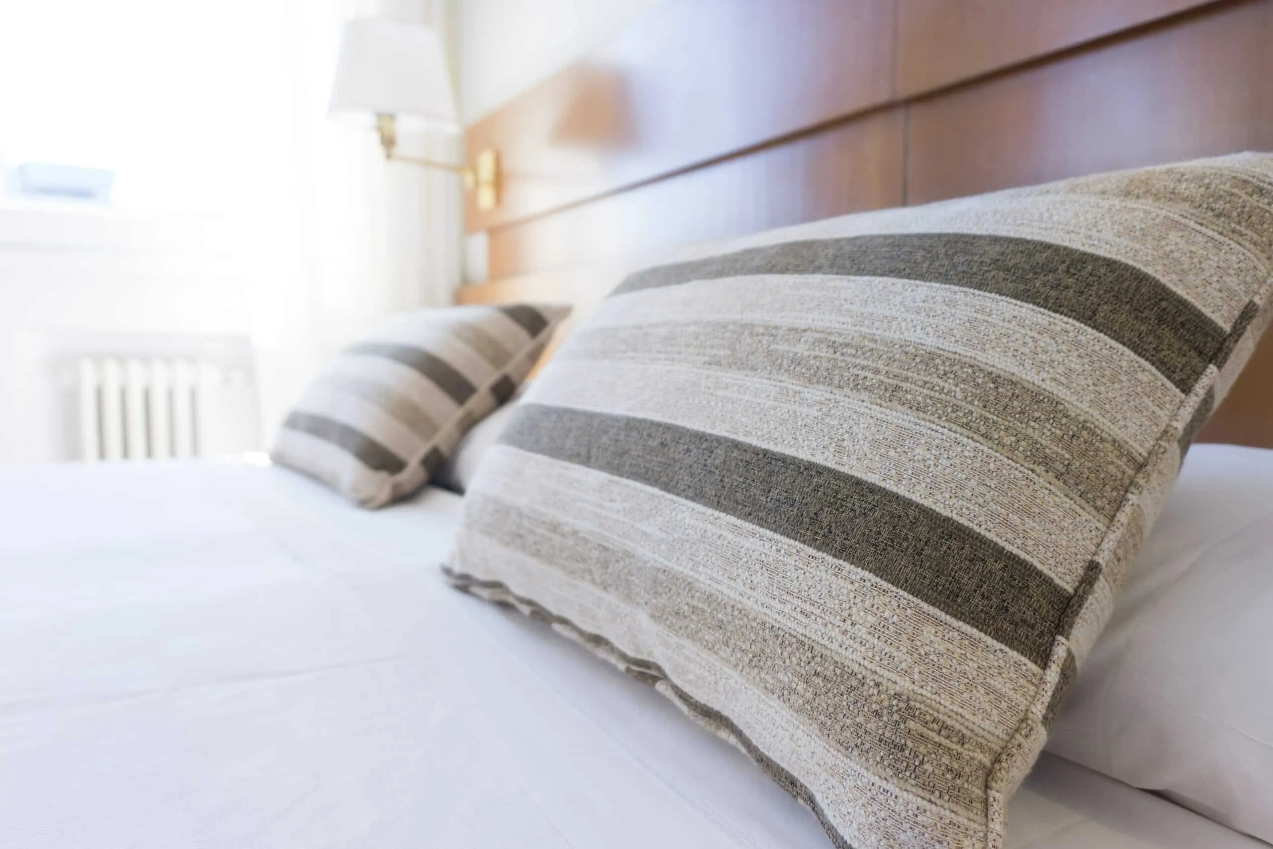 Two striped pillows on a bed in a modern bedroom