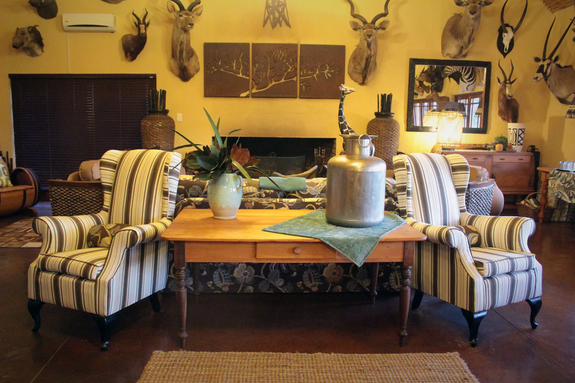 Two striped chairs wooden table and mounted animal heads in a rustic room