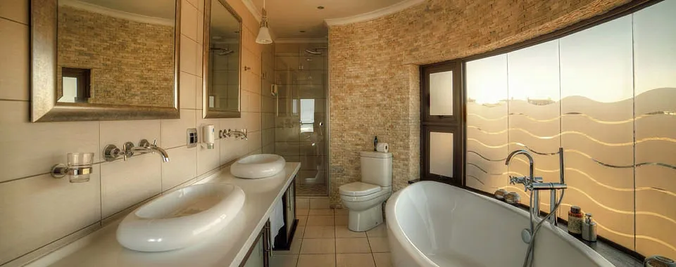 Modern bathroom with dual sinks toilet bathtub and large window with frosted glass