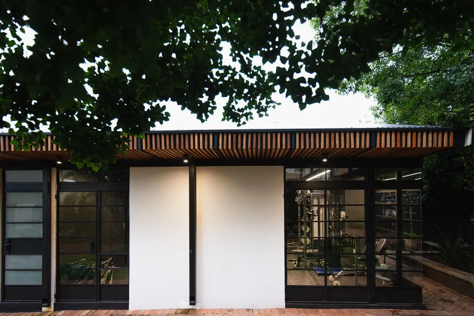Modern building with large windows and wooden slats surrounded by trees