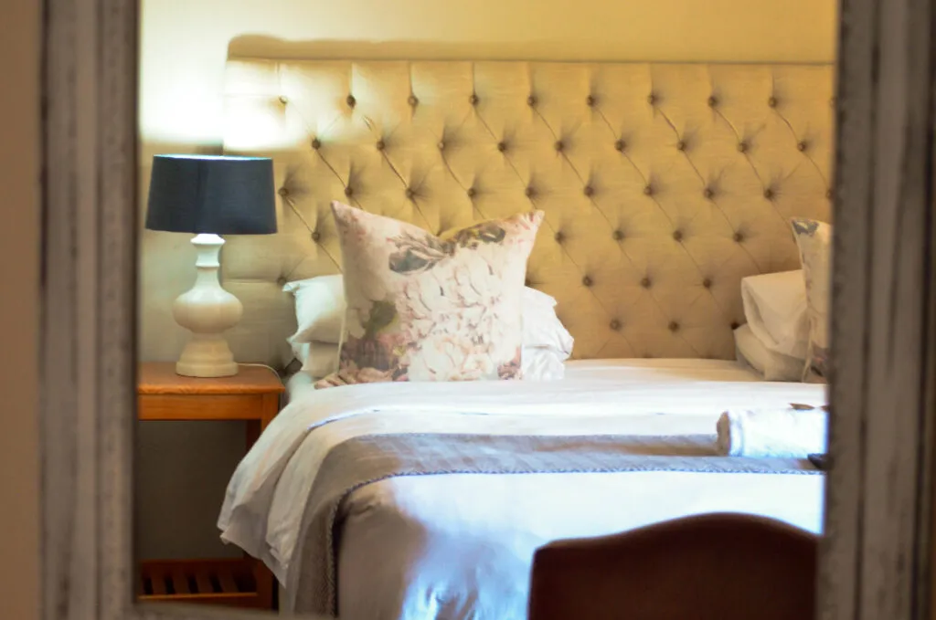 Cozy bedroom with a neatly made bed bedside lamp and floral pillow