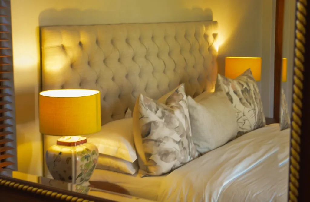 Bed with yellow lamps patterned pillows and white linens in a bedroom
