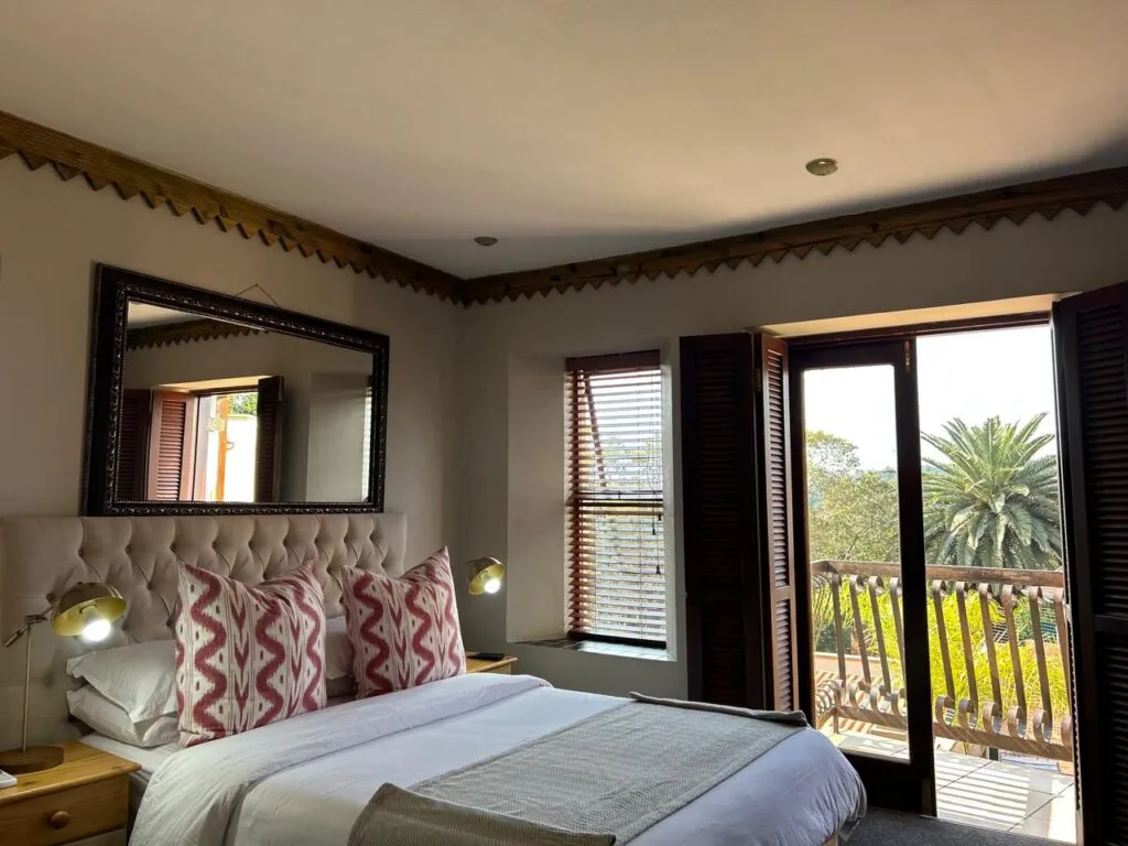 Bright bedroom with large mirror patterned pillows and open balcony doors
