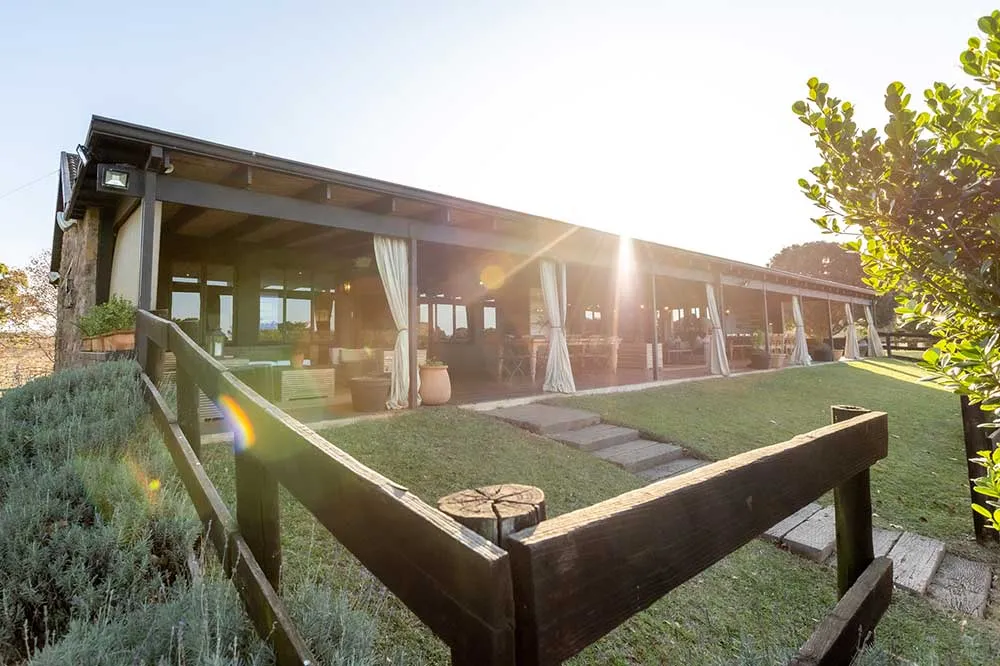 Wooden fence in front of a rustic outdoor dining area with draped curtains