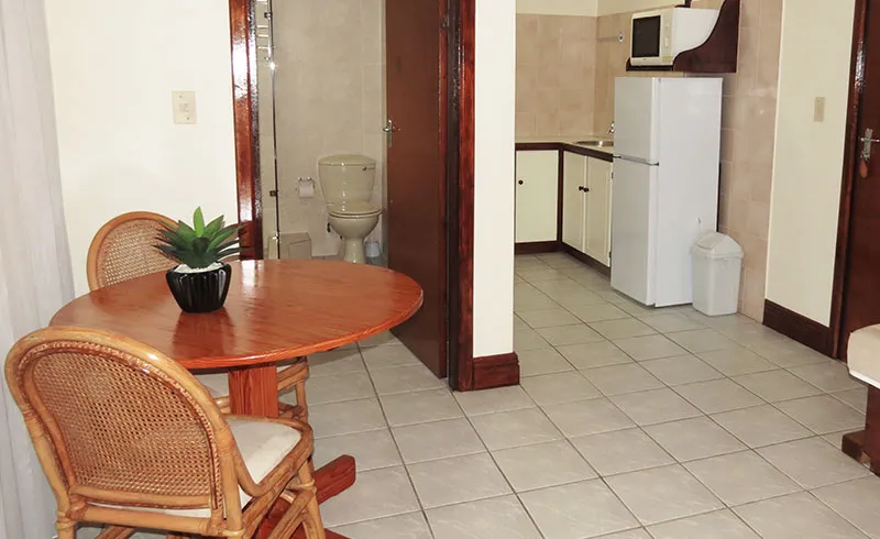 Small kitchenette with dining table visible bathroom and refrigerator in a compact room
