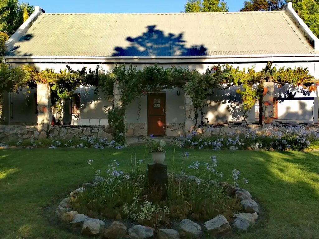Stone cottage with garden flowering plants and climbing vines on the facade