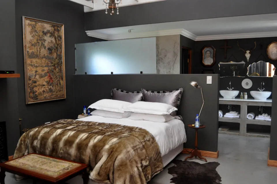 Modern bedroom with a large bed fur throw and adjacent bathroom area