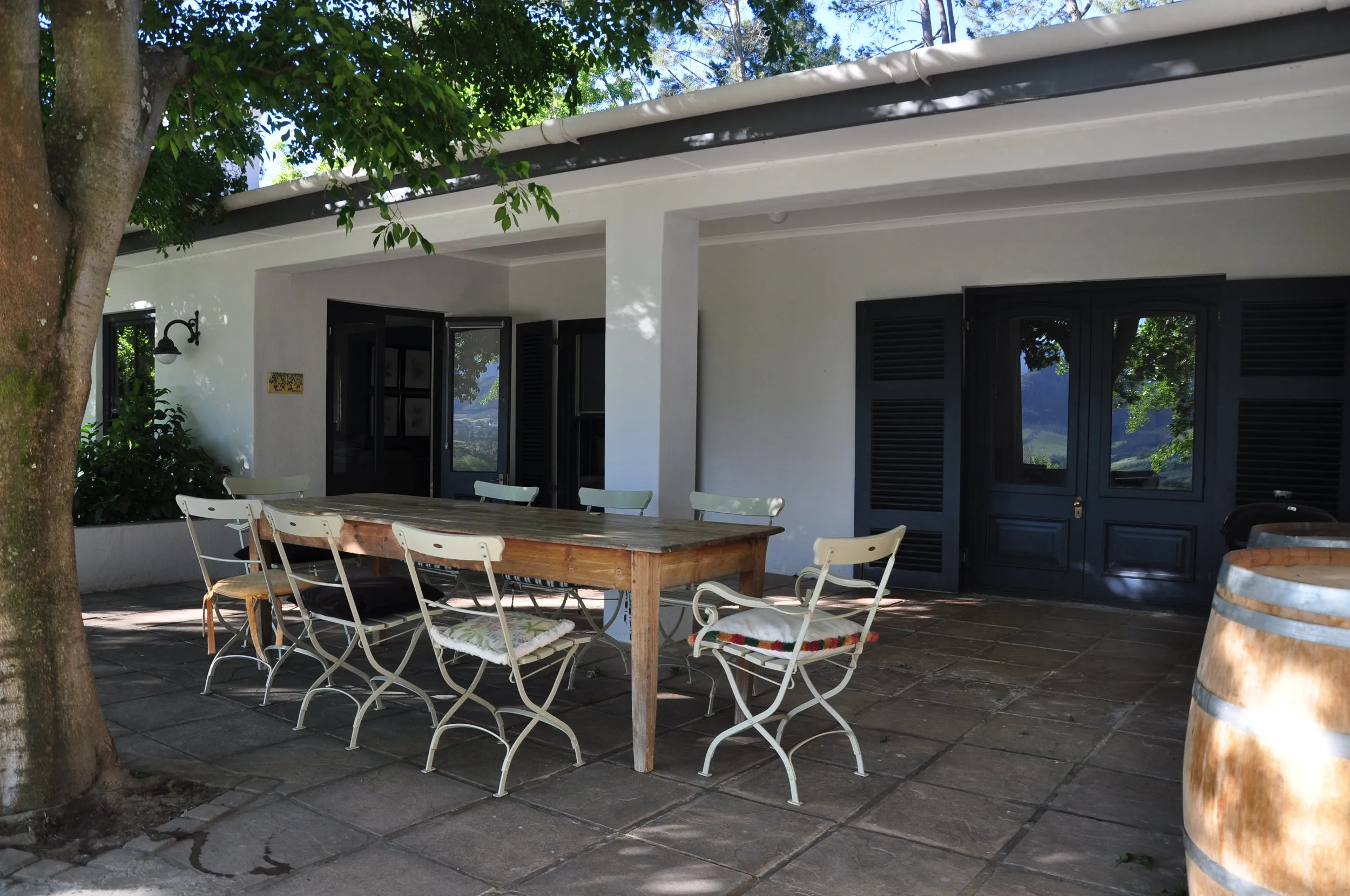 Outdoor dining area with table and chairs under a tree by a house