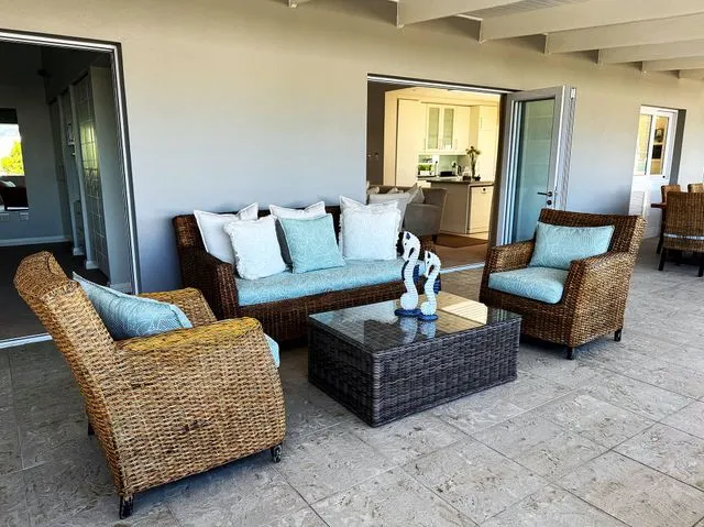 Wicker outdoor furniture set with blue cushions on a tiled patio