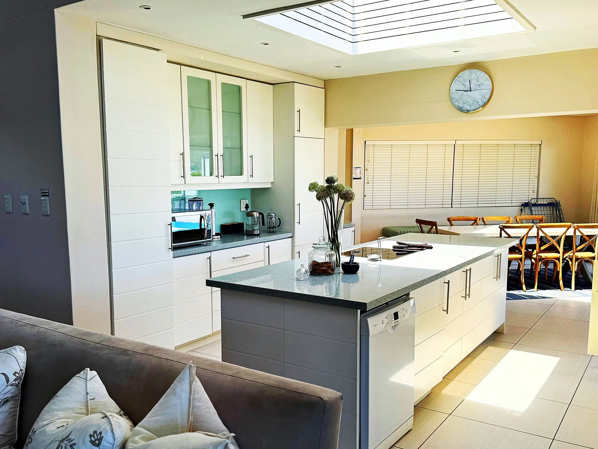 Modern kitchen with island clock on wall and dining area in background