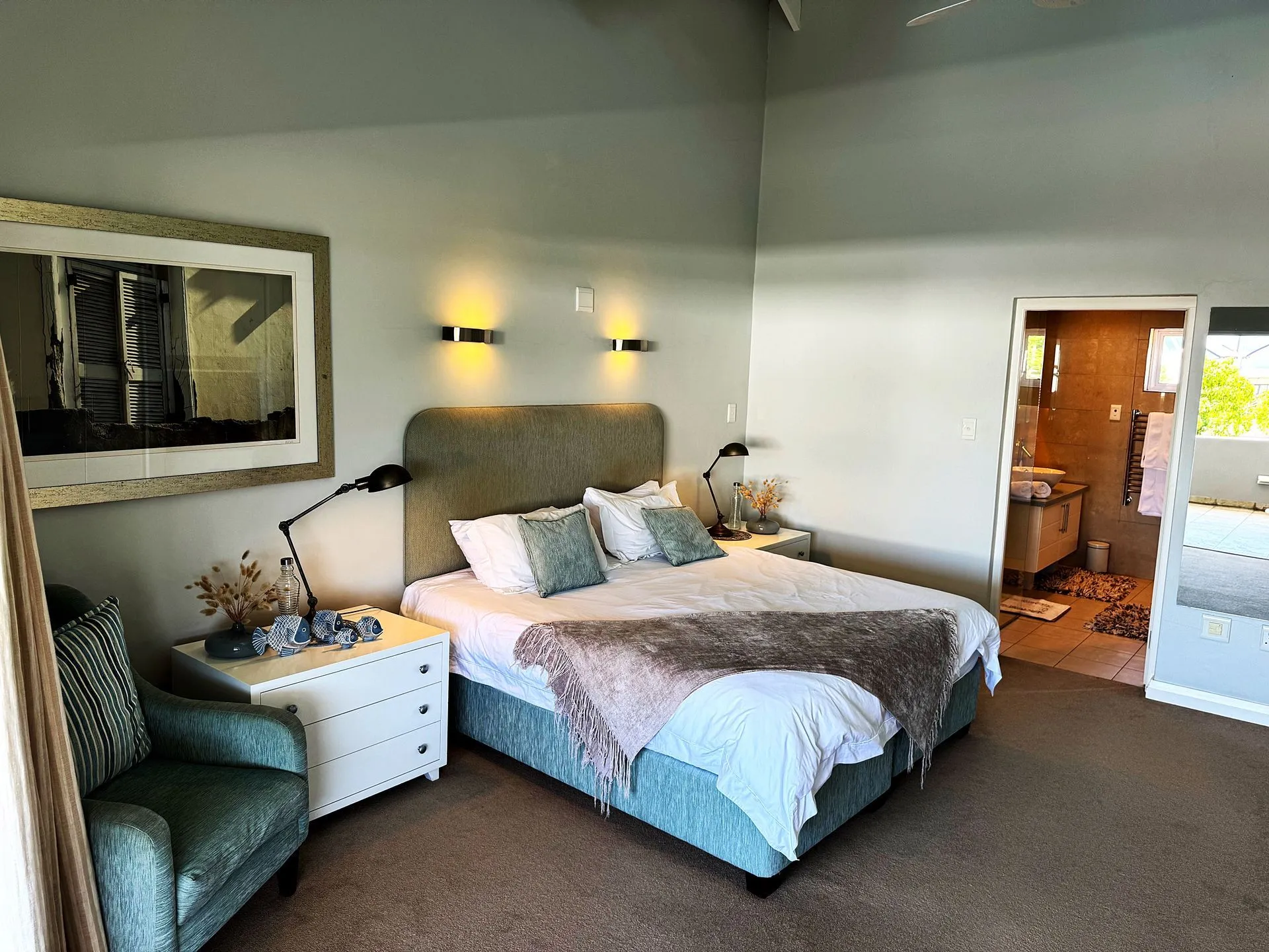 Modern bedroom with large bed armchair and open bathroom door