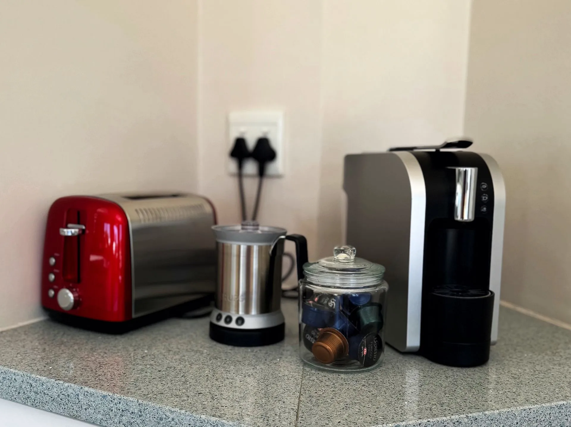 Red toaster silver kettle and coffee machine on a kitchen counter