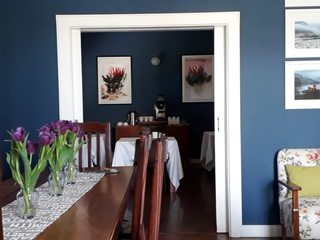 Dining area with wooden table chairs and floral paintings on blue walls