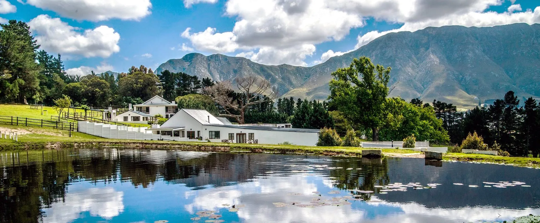 White house by a lake with mountains and trees in the background