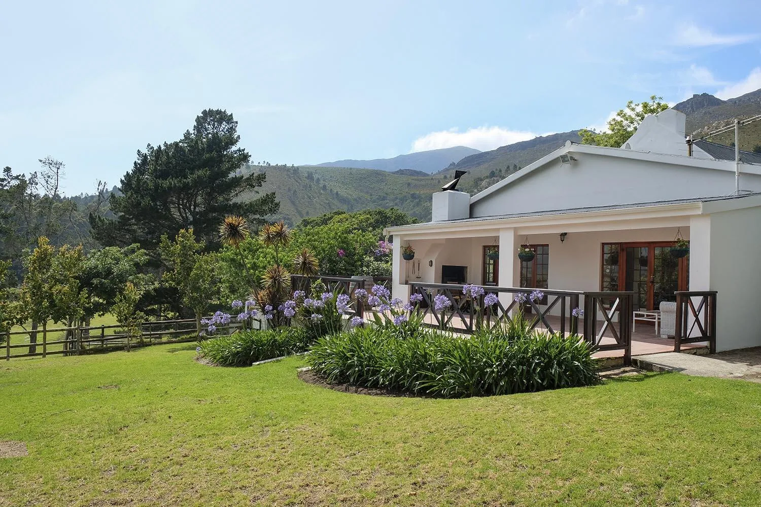 White house with garden and mountains in the background on a sunny day