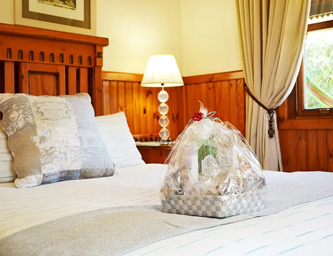 Gift basket on a bed in a cozy wooden bedroom with soft lighting