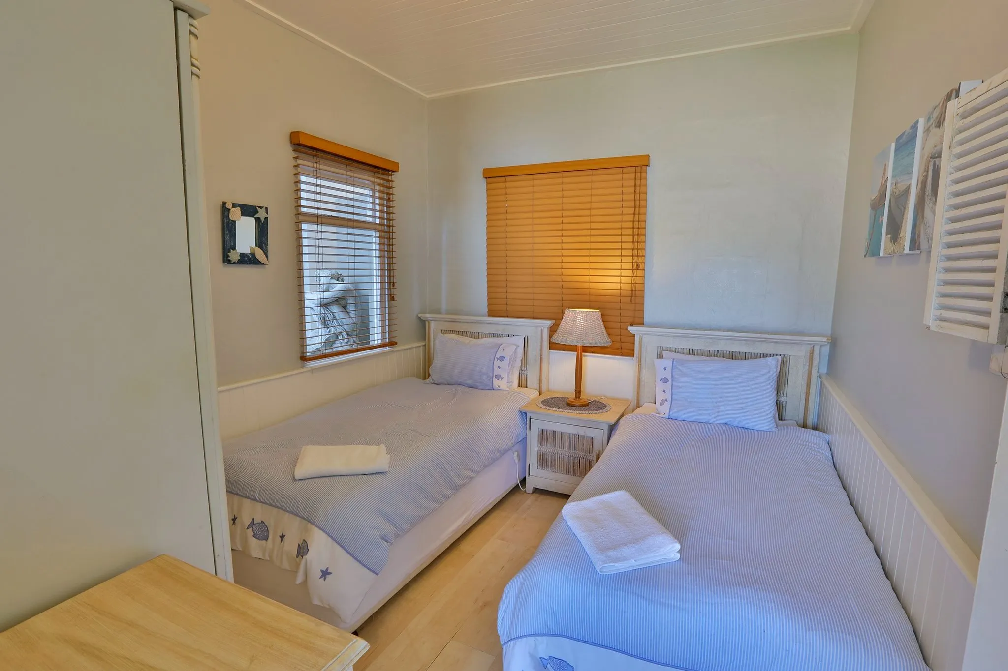 Two single beds in a small bright bedroom with wooden blinds