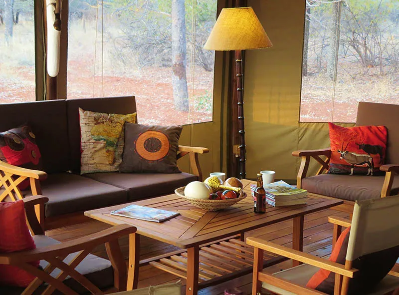 Cozy living area with wooden furniture cushions and a fruit basket on a table