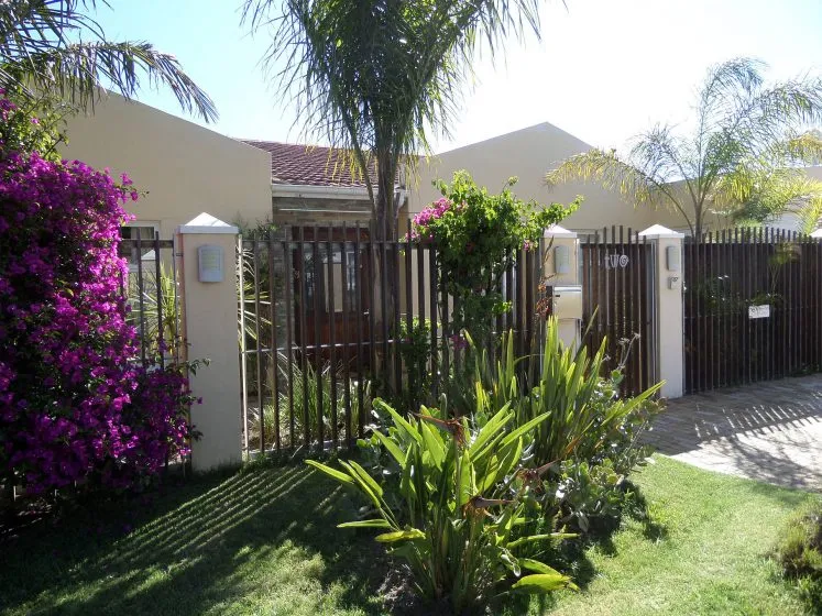 House with wooden fence green lawn and colorful flowers in front