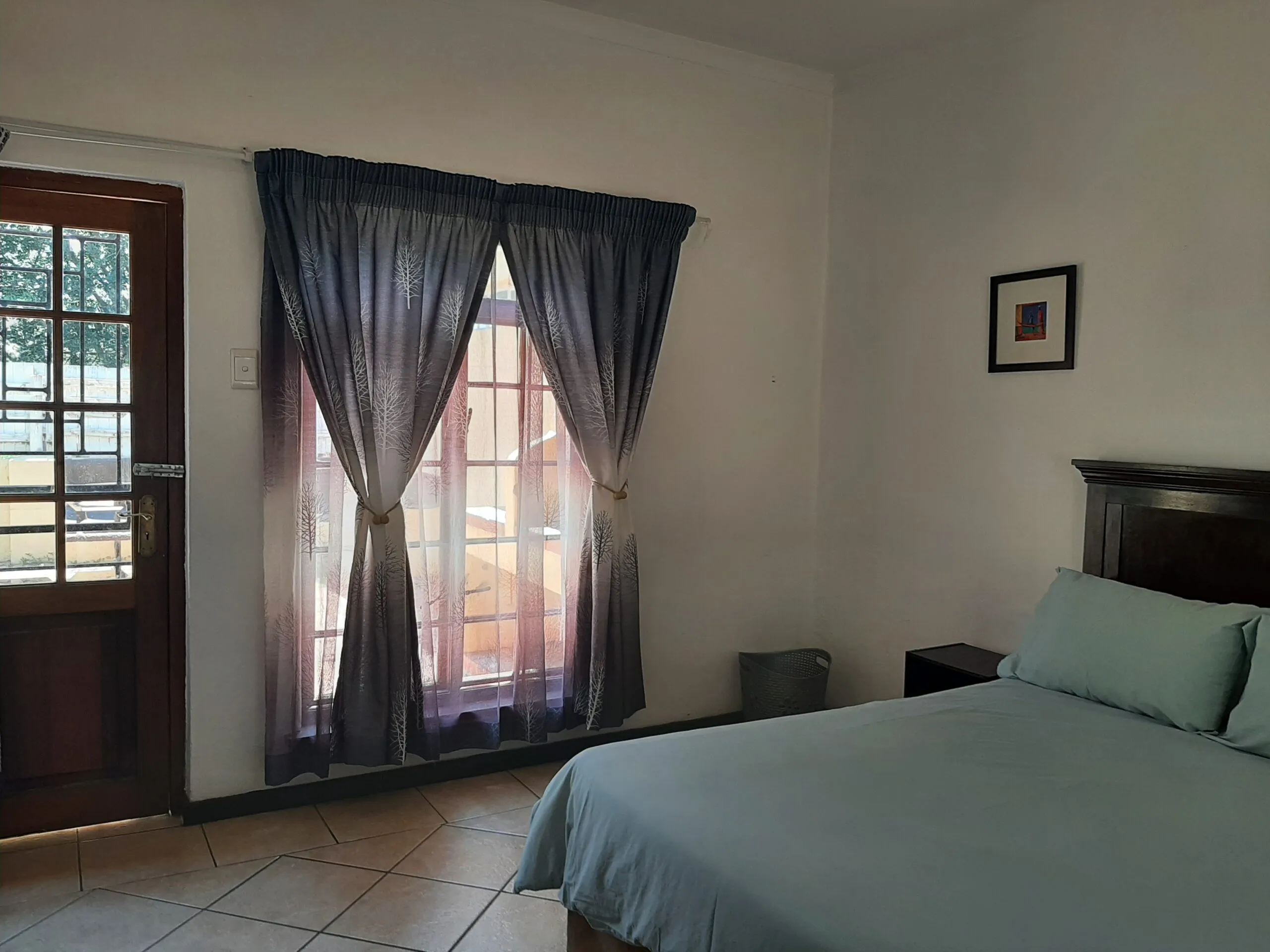 Bedroom with a bed window with curtains and a wooden door