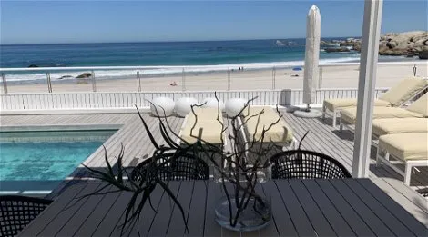 Ocean view from a deck with pool lounge chairs and dining table