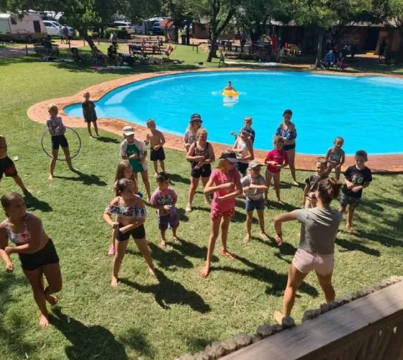 Group of children playing near a swimming pool in a park setting