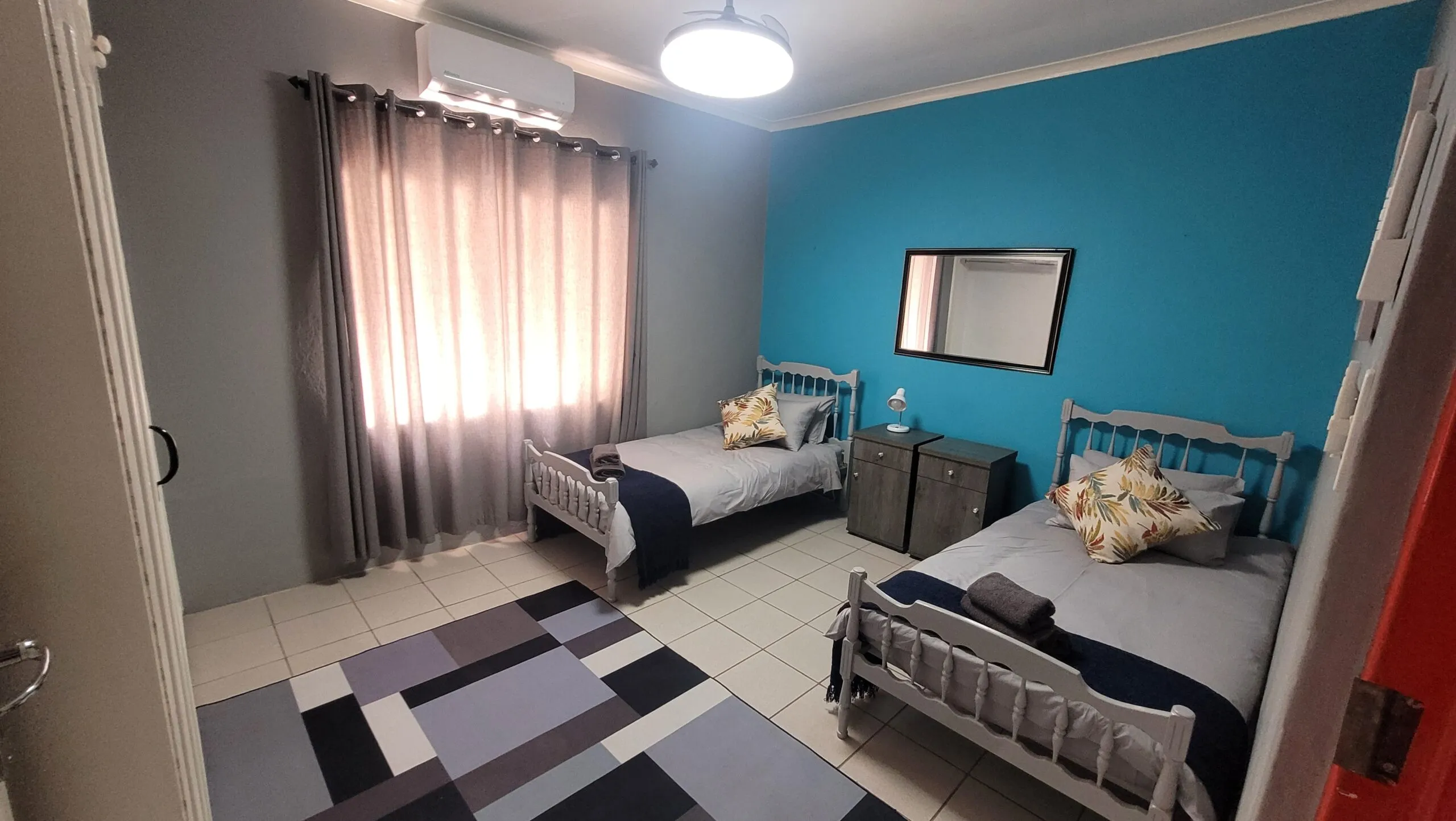 Bedroom with two single beds blue and gray walls and a patterned rug