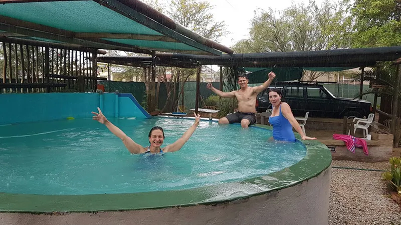 Three people enjoying a swim in an outdoor pool with a slide