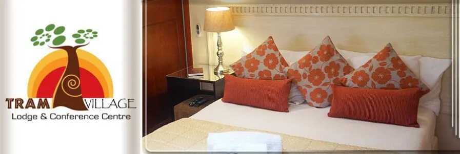 Cozy hotel bed with orange and white pillows bedside lamp and logo