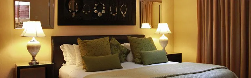 Cozy bedroom with a bed green pillows and bedside lamps on nightstands