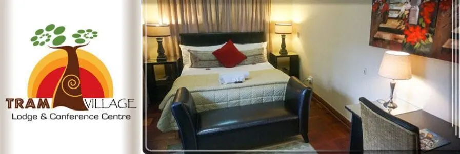Bedroom with a bed desk and lamp logo of Tram Village Lodge Conference Centre