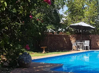 Swimming pool with patio furniture surrounded by greenery and brick wall