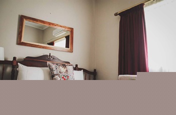 Wooden bed with pillows mirror above and red curtain in a cozy room