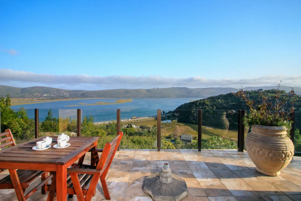 Outdoor patio with table chairs and view of lake and hills