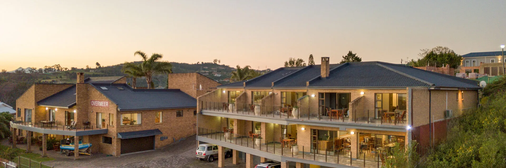 Modern apartment complex with balconies set in a hilly residential area at dusk